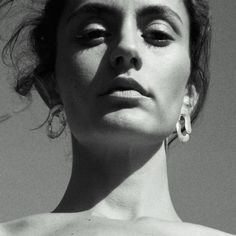 a black and white photo of a woman wearing earrings