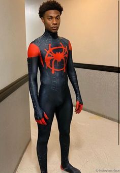 a man in a spiderman suit standing in a hallway