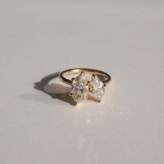 a three stone diamond ring sitting on top of a white surface with no one around it