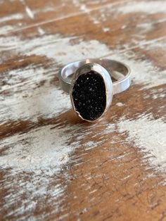 "☾ BLACK DRUZY RING - SIZE 7 ☾ Handmade from sterling silver, this ring is hypoallergenic and crafted with love and attention to detail. The ring is sturdy - so you never have to worry about it breaking with everyday wear - and made from 100% natural materials. It features black titanium-coated druzy as the centerpiece gemstone. This piece would look great on you or it could make the perfect gift! This ring is great for every day wear or to give as a gift. It will come packaged in a padded jewelry box and ready to give as a gift. All of our packaging (filler, box, padding) is 100% biodegradable. ☾ THE DETAILS ☾ * Handmade sterling silver ring - U.S. Size 7 * Black titanium-coated druzy set in ring - 3/8\" x 1/2\" ☾ CARE INSTRUCTIONS ☾ * Don't let lotions, perfumes, or makeup come in contac Black Sterling Silver Stackable Jewelry, Stackable Black Sterling Silver Jewelry, Nickel-free Black Open Ring Jewelry, Nickel-free Black Open Ring, Sterling Silver Large Stone Promise Ring, Minimalist Large Stone Ring For Anniversary, Minimalist Hand Forged Black Rings, Hand Forged Black Rings, Nickel Free Black Promise Ring