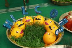 some oranges are sitting in a bowl with letters and numbers painted on them to look like faces