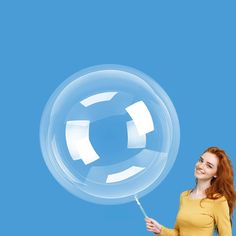 a woman holding a large bubble balloon in her hand and smiling at the camera, against a blue background