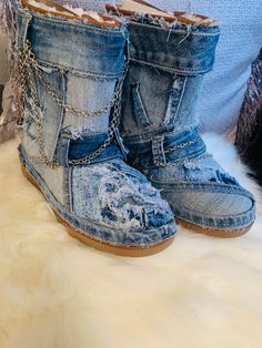 a pair of denim boots with chains on them sitting on a white fur covered bed