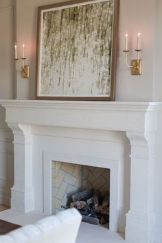 a living room with a fire place and two candles on the fireplace mantels