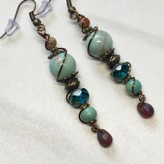 These beautiful unique earrings are made with stone and fire polished glass Czech beads. They are warped with brass wire and have brass hooks on them. They are 2 inches long from the bottom of the hook to the bottom teardrop bead. Will be shipped free USPS first class mail. Bronze Wire Wrapped Czech Glass Earrings, Bronze Wire Wrapped Earrings With Czech Glass, Czech Glass Teardrop Dangle Earrings With Ear Wire, Artisan Dangle Earrings With Faceted Beads, Unique Wire Wrapped Beaded Drop Earrings, Unique Adjustable Teardrop Earrings With Ear Wire, Wire Wrapped Czech Glass Teardrop Beaded Earrings, Beautiful Pendant Necklace, Brass Hooks