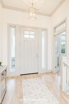 an empty entryway with white walls and wood floors is seen in this image from the front door