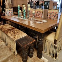 a wooden table surrounded by chairs and rugs with fringed seats on them in a store