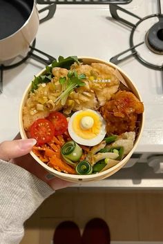 a person holding up a bowl of food on top of a stove with an egg in it