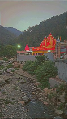 a large red and yellow building sitting on top of a hill next to a river