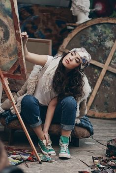 a woman sitting on the ground with an easel