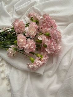 pink carnations are laid out on a white sheet