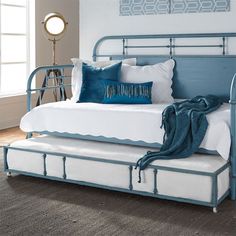 a blue metal daybed with white sheets and pillows