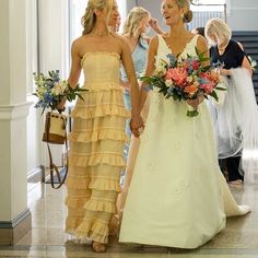 two bridesmaids walking down the aisle holding hands and smiling at each other with flowers in their hand