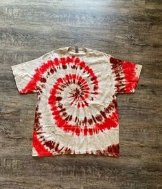 a red and white tie - dyed t - shirt sitting on top of a wooden floor