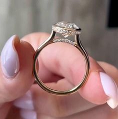 a close up of a person's hand holding a ring with a diamond on it