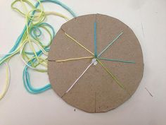 a circular piece of paper with yarn on it next to a round object that has been made out of cardboard