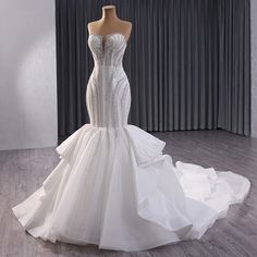 a white wedding dress on display in front of a curtain