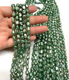 a hand is holding some green beads