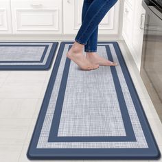 a woman standing on the kitchen floor in front of two rugs that are both blue and white