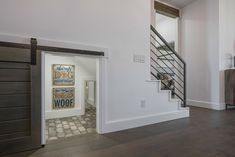 an open door leading to a living room with stairs and artwork on the wall behind it