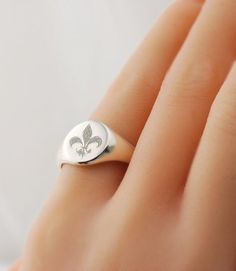 Fleur-de-lis Custom engraved signet ring in pure sterling silver. * Choose from various US ring sizes * Solid .925 Sterling Silver ~ Hallmarked * Made in the U.S.A. * Features a signet pad that measures approximately 11 x 9 mm for personalization (varies by ring size) PERSONALIZATION OPTIONS ✤ Can be engraved with any other design, logo or symbol too ❤ ☯ ✡ ✞ ★ (ask me how). ✤ Monogram with initials >> https://www.etsy.com/listing/125136982 IMPORTANT Please be sure to know your exact ring s Flower Logos, Family Crests, Fingerprint Jewelry, Signet Rings, Silver Signet Ring, Flower Logo, Themed Jewelry, Engraved Rings, Signet Ring