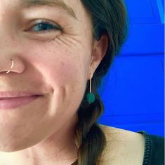 a close up of a person wearing earrings and smiling at the camera with a blue background