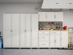 an organized garage with white cabinets and tools