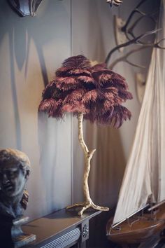 a lamp that is on top of a table next to a statue and a sailboat