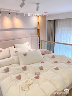 a bed with white sheets and pink hearts on the comforter in front of a window