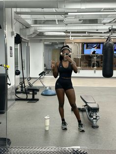 a woman standing in a gym with headphones on