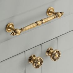 two handles on a white cabinet with gold knobs