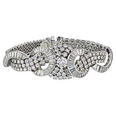 Crafted with unparalleled artistry and adorned with the most exquisite diamonds, our Art Deco Platinum Cluster Diamond 38.00cttw Bracelet is a testament to timeless elegance. Every aspect of this remarkable piece is a celebration of beauty and craftsmanship, designed to captivate the heart of your beloved. The bracelet boasts a stunning composition of round and baguette-shaped diamonds, meticulously arranged to form a breathtaking cluster on the wrist. At the center lies a magnificent 1.80ct rou Art Deco Diamond Jubilee Bracelet, Luxury Platinum Diamond Bracelet With Baguette Diamonds, Art Deco Diamond Tennis Bracelet With Brilliant Cut, Luxury Diamond Evening Bracelet, Luxury Platinum Diamond Bracelet With Single Cut Diamonds, Luxury Evening Diamond Bracelet, Timeless Hand Set Platinum Diamond Bracelet, Exquisite Platinum Diamond Bracelet With Brilliant Cut, Platinum Diamond Bracelet With Brilliant And Baguette Cut