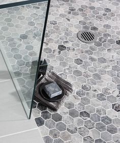 a bathroom with hexagonal tiles and a glass shower door that has a towel on it