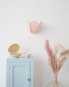 a vase with some flowers on top of it next to a wall mounted paper heart