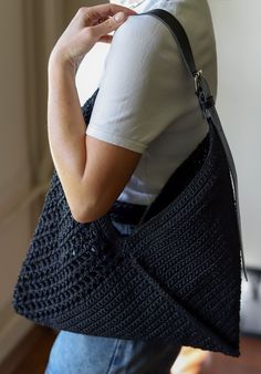 a woman carrying a crocheted black purse