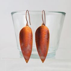 *Please see the last two pictures for the current batch of these unique earrings* These earrings are made in small batches of 3 pairs at a time so please select the pair you would like from the current batch These large copper leaf earrings are sure to make an impression wherever they're worn The long leaf-shaped copper earrings have been torch fired to give a unique flame coloured oxidized copper effect, which hang from your choice of either hand crafted polished copper or sterling silver ear wires The earrings are approximately 63mm long and are available with your choice of polished copper or sterling silver earwires *To retain the unique colours, it is important that these earrings are not polished as any polishing products will remove the oxidised finish* These earrings come presented Oxidised Copper, Earrings Oxidised, Copper Jewellery, 7th Anniversary Gifts, Copper Leaf, Hammered Earrings, 7th Anniversary, Oxidized Copper, Le Lot