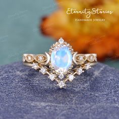 an opal and diamond ring sits on top of a blue rock with leaves in the background