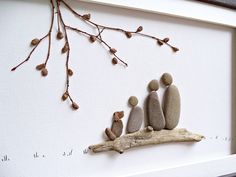 three rocks sitting on top of a tree branch in front of a white framed wall