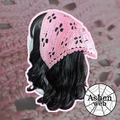 a crocheted pink hat with black spots on it and a spider web in the background