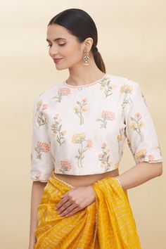 White saree blouse with all-over yellow-peach floral motif embroidery and lace trim sleeve hem.
Component: 1
Embroidered
Neckline: Round
Sleeve Length: Half
Fabric: Chanderi
Color: White
Closure: Back placket
Note: Saree worn by the model is not for sale - Aza Fashions Spring Wedding Blouse With Chikankari Embroidery, Spring Wedding Blouse With Resham Embroidery, Yellow Resham Embroidery Top For Spring, Spring Yellow Tops With Resham Embroidery, Festive White Blouse With Embroidered Sleeves, Spring Wedding Blouse Piece With Floral Embroidery, Spring Wedding Blouse With Floral Embroidery, Tops With Embroidered Sleeves For Wedding And Spring, Spring Tops With Embroidered Sleeves For Weddings