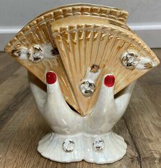 two white ceramic birds with red nail polishes on their feet, one holding a fan