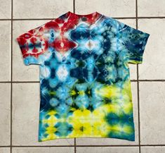 a tie - dyed t - shirt sitting on a tile floor