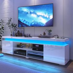 a flat screen tv sitting on top of a white entertainment center next to a plant