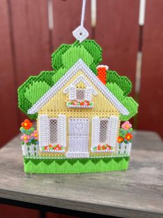 a small house ornament hanging from a string on top of a wooden table