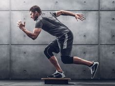 a man in grey shirt and black shorts running on a skateboard with his hands out