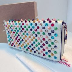 Christian Louboutin's Panettone Wallet Features A Zip-Around Top With Signature Red Sole Pull Charm And Red Leather Lining. A Fun And Distinguished Wallet Embellished With Multicolor Metal Spikes. There Are 12 Credit Card Slots, Four Slip Pockets, Two Bill Pockets, And One Interior Zip Pocket. Height : 4.13” Width : 7.68” Luxury Multicolor Clutch, Designer Multicolor Wallets With Card Slots, Luxury Multicolor Leather Wallets, Luxury Multicolor Wallets With Card Slots, Louboutin Bags, Metal Spikes, Red Sole, Red Leather, Card Slots