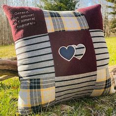 a pillow with two hearts on it sitting in the grass next to a tree branch