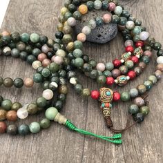 Beautiful Mix Jade Japa Mala from Nepal. You can choose between the mala that has unique mix metal beads and a main Nepali metal bead at the bottom of the mala necklace. Or the mix Jade mala that is all stone beads with no metal beads. A unique praying mala that can be used as a necklace or as an ornament. The mala has no clasp, you wear it over the head. The Mala with the metal beads and the red beads has a total length of 49cm- 19.25 inch long The mala that is all stone beads is 43cm- 17 inch Green Mala With 8mm Beads For Healing, Green Spiritual Beads For Healing, Spiritual Healing Beaded Bracelets With Oval Beads, Green Spiritual Beads, 108 Count, Holistic Beaded Bracelets With Round Beads For Meditation, Spiritual Colorful Beads Bracelet, Spiritual Oval Beads For Jewelry Making, Hand-strung Multicolor Round Beaded Necklaces, Holistic Multicolor Gemstone Beaded Necklaces