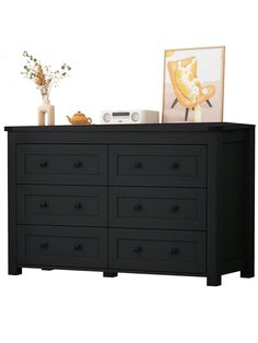 a black dresser with drawers and pictures on top