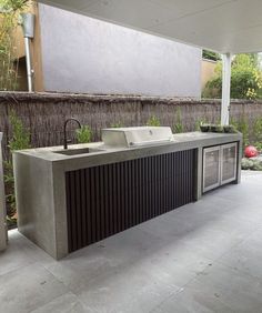 an outdoor kitchen with two sinks and a grill on the outside wall next to it